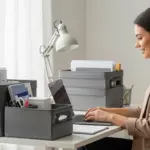 Woman working on a laptop at a desk with portable storage containers.